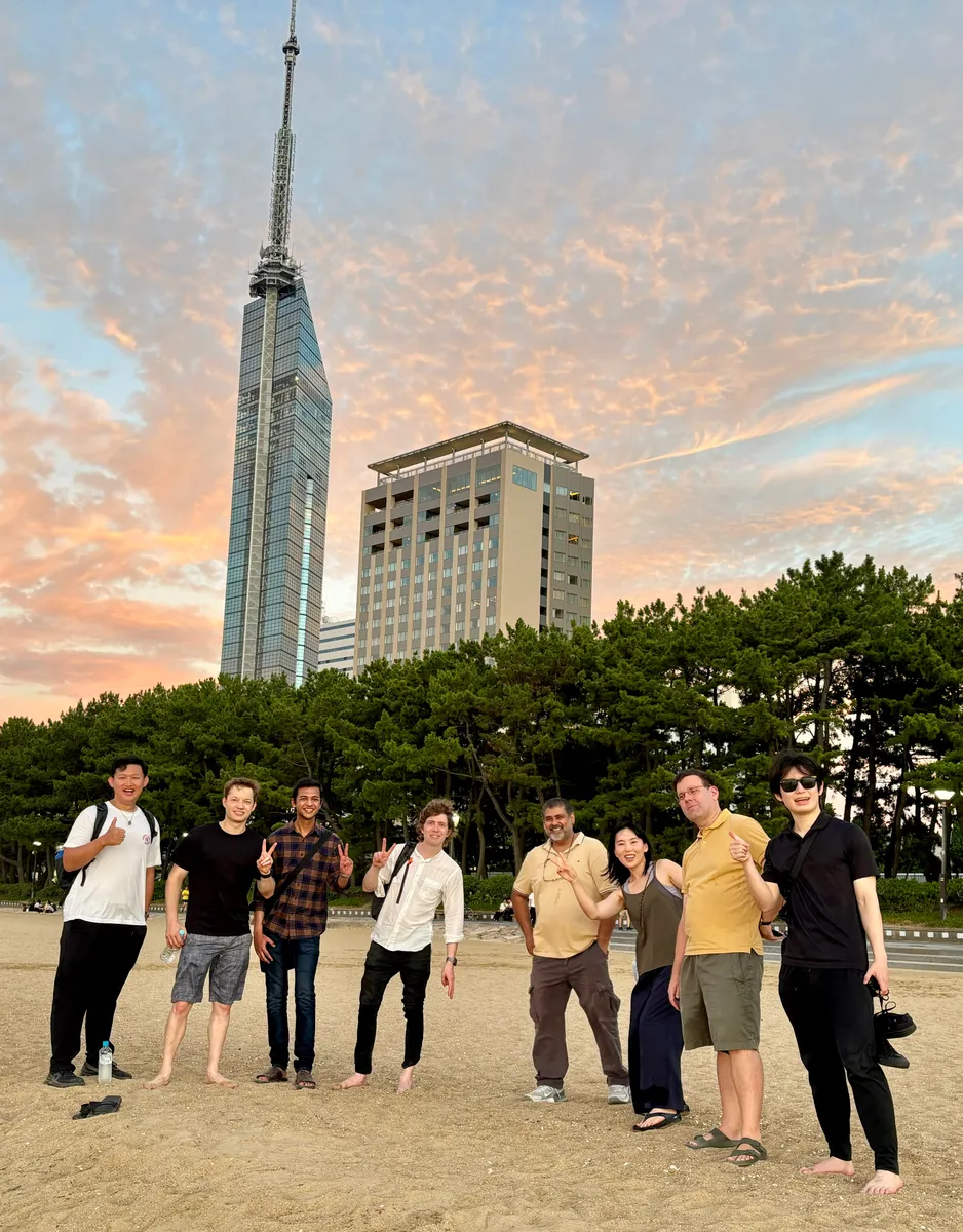 Members on the beach below Fukuoka Tower at sunset